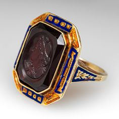 This unique and special circa 1900 Victorian intaglio ring features engraved details along the top and side faces with blue and orange enamel. The ring is accented with one (1) bezel set cut-cornered rectangular shaped intaglio cut garnet. The ring measures 20.7mm at the top, rises 6.5mm above the finger, tapering to 1.6mm wide and 1.0mm thick at the base of the shank. It is a size 4.75 and we are not offering resizing due to the enamel on the ring. It shows average wear for its age. Art Deco Enamel Rings For Formal Occasions, Art Deco Yellow Gold Enamel Ring For Formal Occasions, Art Deco Formal Yellow Gold Enamel Ring, Formal Yellow Gold Art Deco Enamel Ring, Formal Art Deco Yellow Gold Enamel Ring, Antique Enamel Ring Collectible, Antique Black Enamel Signet Ring, Antique Enamel Rings For Collectors, Antique Enamel Rings As Collectibles