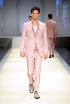 a man in a pink suit walks down the runway