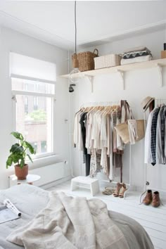 a bedroom with white walls and shelves filled with clothes