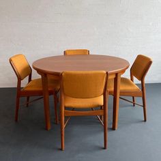 a table with four chairs around it and a white wall in the backround