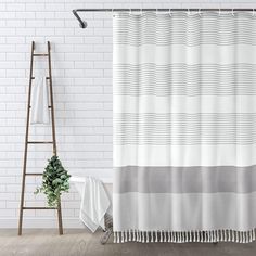 a bathroom with a shower curtain, towel rack and potted plant on the floor