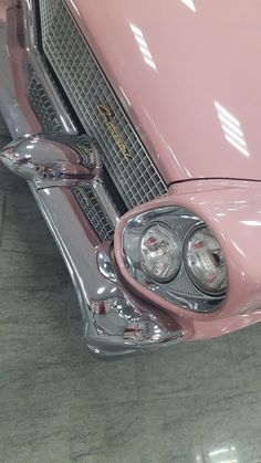 the front end of an old pink car