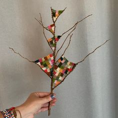 a person holding a branch with small pieces of fabric on it