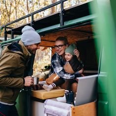 a group of people standing in the back of a green van with food and drinks