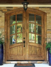 two large blue planters are sitting in front of a wooden door with glass panes