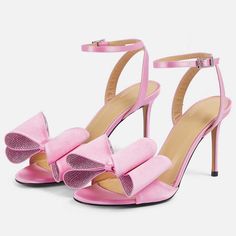 Elevate your style with these pink satin heeled sandals. Featuring an open toe design, elegant bow detail, shimmering crystal embellishments, and a secure ankle strap, perfect for chic women. Color: Pink Heel Type: Stiletto heel Heel height: 4" / 100 mm approx Product measurements were taken using size 8. Please note that measurements may vary by size. Toe: Open toe Adjustable ankle strap design Faux crystal bow embellishment Handcrafted US sizing. Fits true to size. Pink Open Heel Heels With Bow, Pink High Heel Sandals With Bow, Pink Ankle Strap Heels With Bow Straps, Pink Open Toe Heels With Bow, Pink Bow High Heels For Summer, Summer High Heels With Pink Bow, Evening Heels With Pink Bow And High Heel, Pink Bow Sandals For Evening, Pink Round Toe Sandals For Prom