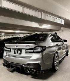 two cars parked next to each other in a parking garage, one is silver and the other is black