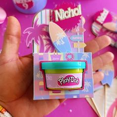 a hand holding up a play doh toy in front of some stickers and magnets