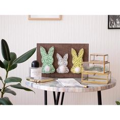 three paper rabbits sitting on top of a table next to a potted plant and pen