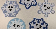 four paper snowflakes with faces and eyes on the side, all decorated in blue and white