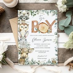 a baby shower is shown with flowers and greenery on the wooden table next to it