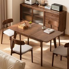 a wooden table and chairs in a living room with a microwave on the wall behind it