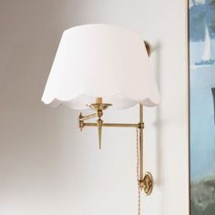 a wall lamp with a white shade on it in the corner of a living room