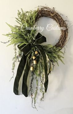 a wreath with greenery and bells hanging on the wall