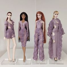 three mannequins dressed in purple dresses with long hair