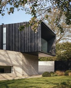 the house is made out of black wood and has a sloping roof that extends into the yard