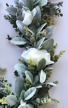 white flowers and green leaves are arranged on the wall