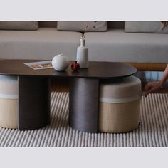 a coffee table with two stools and a vase sitting on top of it in front of a couch