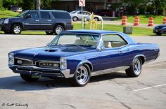 an old muscle car parked in a parking lot