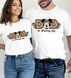 a man and woman standing next to each other in front of a white wall wearing matching tshirts