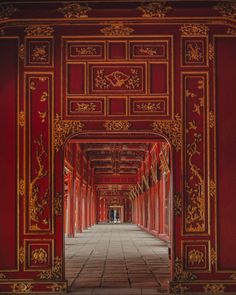 an archway with red walls and gold decorations on the sides, leading to another room