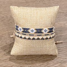 two blue and white beaded bracelets are sitting on top of a beige pillow