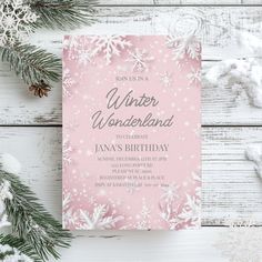 a pink and white winter wonderland birthday party with snowflakes on the table, pine branches