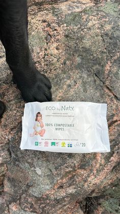 a dog paw reaching for a bag of eco baby wipes on top of a rock