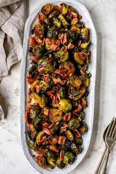 brussel sprouts with bacon in a serving dish next to a fork