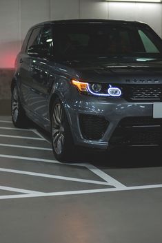 a grey range rover parked in a parking garage with red lights on the side of it