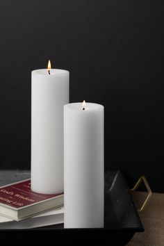 two white candles sitting on top of a tray