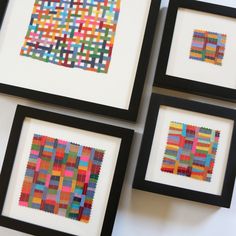 four framed art pieces with different colored squares in black frames on a white table top