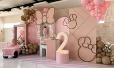 a room decorated in pink and gold with balloons on the wall, minnie mouse decorations