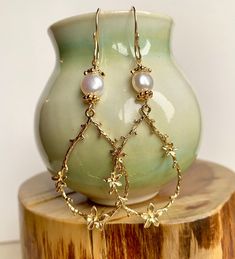 Enhance your boho chic style with this set of long gold teardrop-shaped flower branch dangly earrings. Featuring large gold-plated brass flower branch charms, these earrings are delicately crafted and exude a sweet charm. The handmade earring hooks, crafted with 10K gold-filled wire, add a touch of elegance. At the top, white freshwater pearls with gold-plated floral bead caps provide a classic and timeless accent. Measuring 2 1/2" X 7/8", including the gold-filled wire hooks, these earrings are a beautiful choice for Christmas gifts, birthdays, weddings, or any special occasion. Embrace the allure of boho chic with these intricate and stylish flower branch earrings. Whimsical Gold Jewelry With Flower Charm, Teardrop Earrings With Flower Charm, Elegant Teardrop Earrings With Flower Charm, Gold Whimsical Flower-shaped Earrings, Gold Flower Chandelier Earrings Elegant Style, Delicate Teardrop Flower Earrings For Pierced Ears, Bohemian Teardrop Yellow Gold Earrings, Bohemian Gold Drop Earrings, Delicate Teardrop Flower Earrings