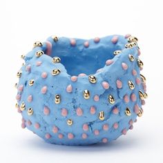 a blue bracelet with pink and gold studs on the outside, sitting in front of a white background