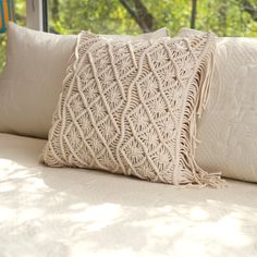 a close up of a pillow on a bed in front of a window with trees outside