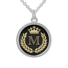 a black and gold monogrammed necklace with the letter m on it's front