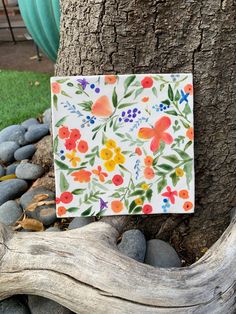 a piece of paper that has been placed on a tree branch and is decorated with colorful flowers