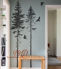 a wall with trees and birds painted on it in a room that has an entry way