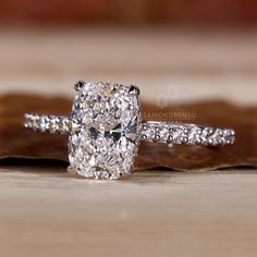 a cushion cut diamond ring on top of a wooden table