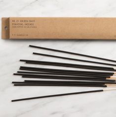 six black chopsticks in a cardboard box on a marble surface