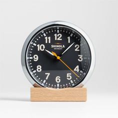 an analog clock on a wooden stand with the word shinola printed on it's face