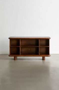 a wooden shelf sitting on top of a cement floor next to a white wall,