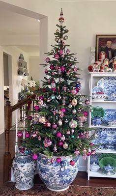 a decorated christmas tree sitting next to two blue and white vases