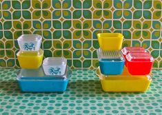 four plastic containers are stacked on top of each other in front of a colorful wallpaper