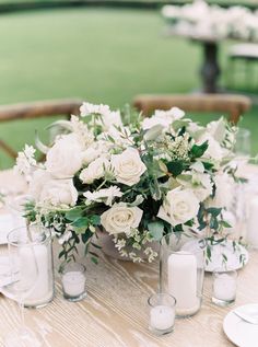 a table with white flowers and candles on it