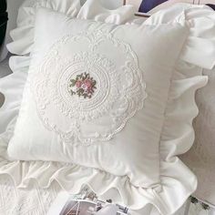 a close up of a pillow on a bed with ruffles and pillows in the background