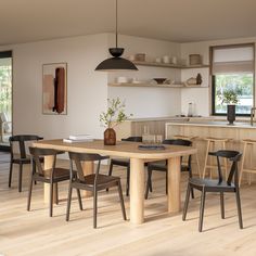 a dining room table surrounded by chairs in front of an open kitchen