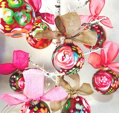 a bunch of ornaments hanging from the side of a wall with ribbons on them and bows attached to each ornament