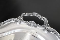 an ornate silver tray on a black background with the handle in the shape of a heart